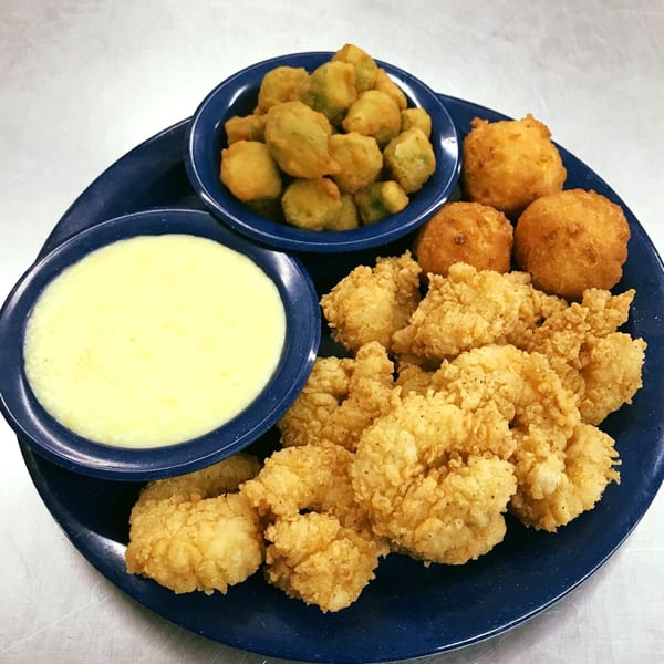 A blue plate with fried catfish, hush puppies, fried okra, and a bowl of grits.